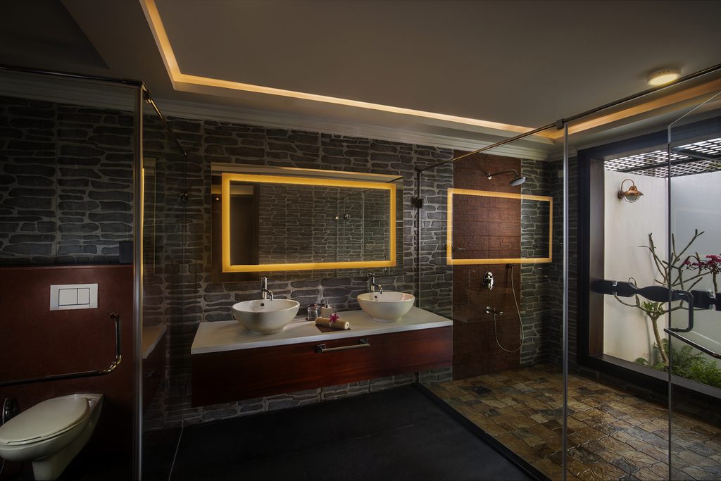 Das stilvoll gestaltete Badezimmer mit Natursteinwänden und Regendusche im Amal Tamara Resort.